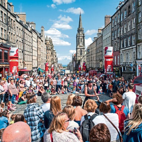 Edinburgh, United Kingdom - July 30, 2013: People following a street performer on the Royal Mile, Edinburgh, Scotland, a few days before the official start of the Fringe Festival (2-26 August), the most famous festival of the street arts of the World.